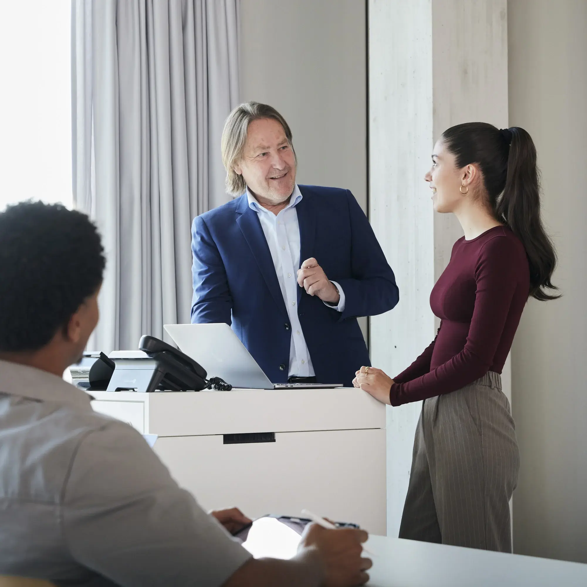 Ein Professor unterhält sich in einer Vorlesung mit einer Studentin am Pult.