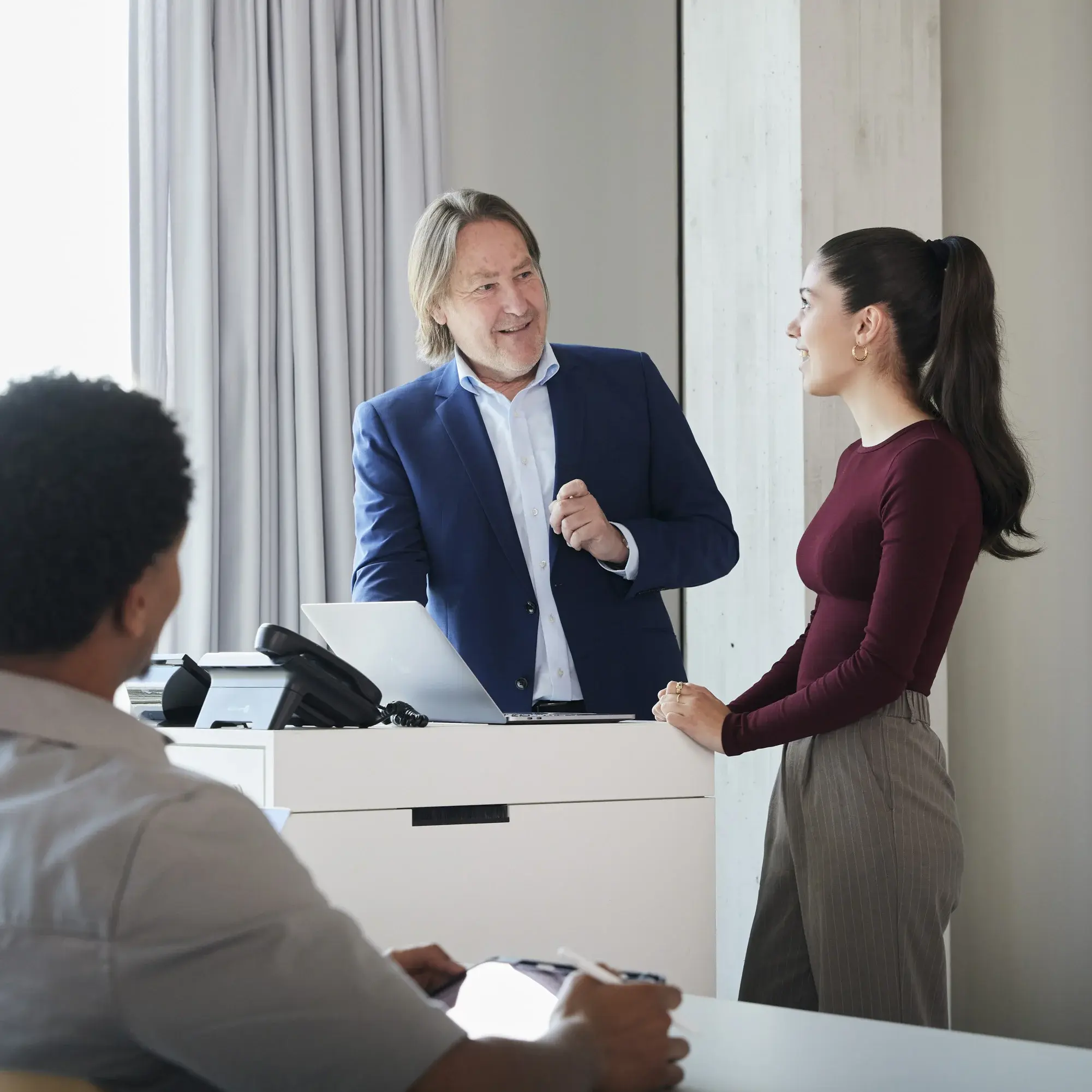 Ein Professor unterhält sich in einer Vorlesung mit einer Studentin am Pult.
