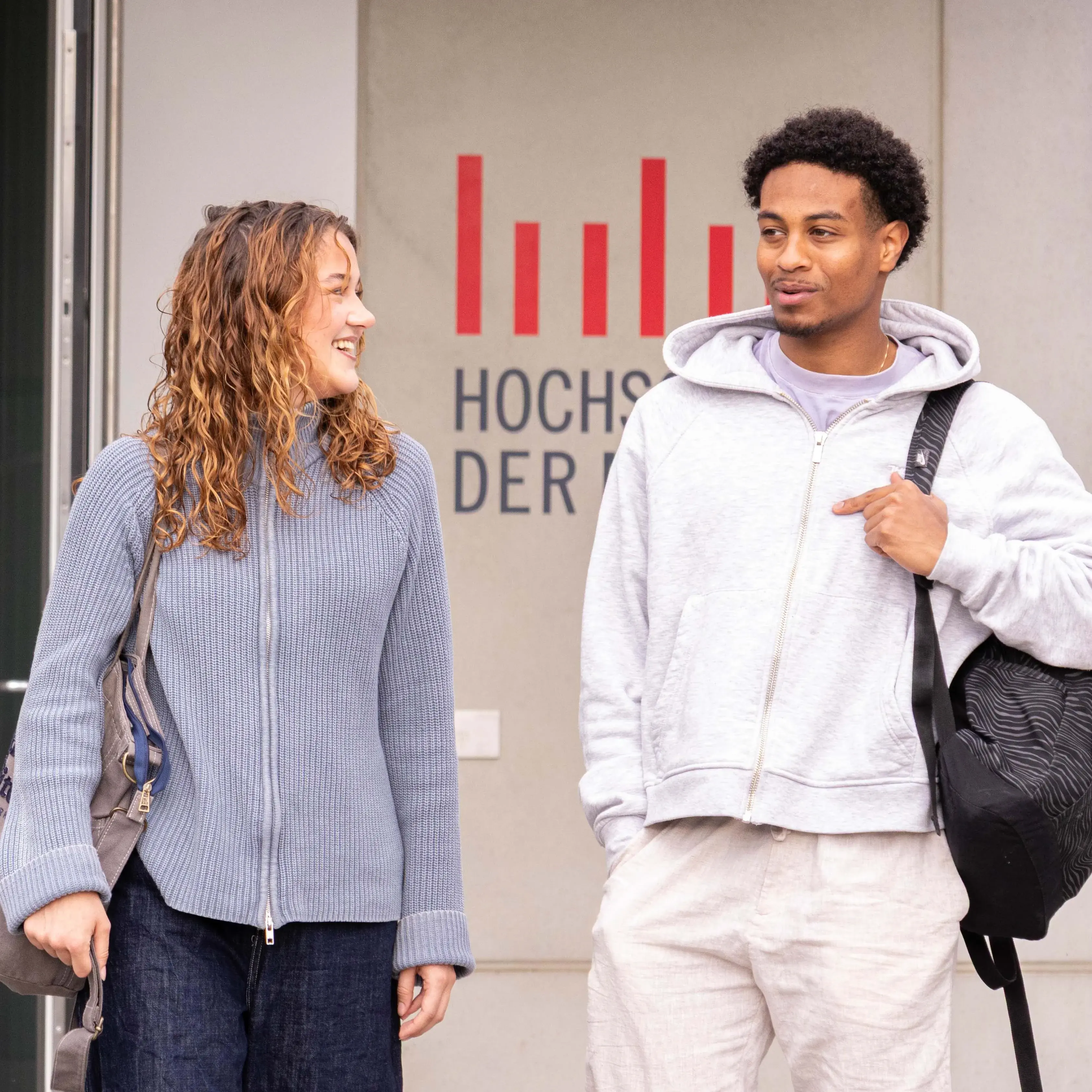 Studierende unterhalten sich beim Verlassen der Hochschule der Medien.